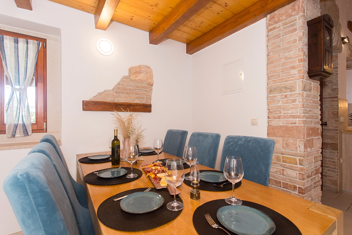 Indoor table with blue chairs, trays of Croatian food, and bottles of Croatian wine on the table.